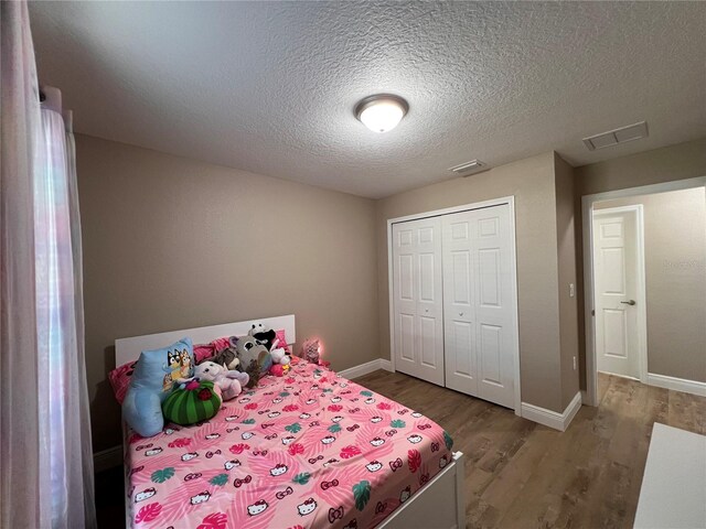 bedroom with a textured ceiling, wood finished floors, and visible vents