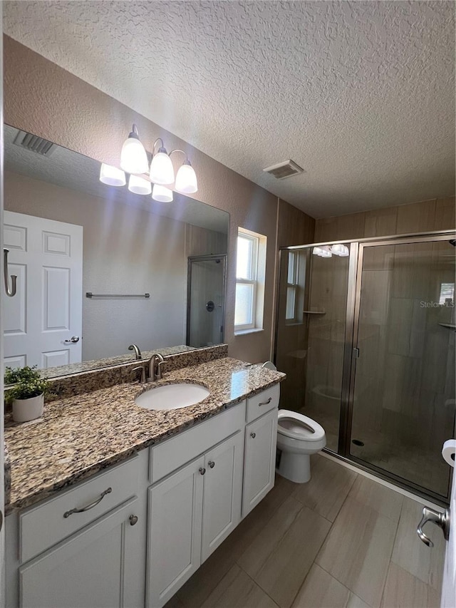 full bathroom featuring visible vents, toilet, vanity, a textured ceiling, and a stall shower