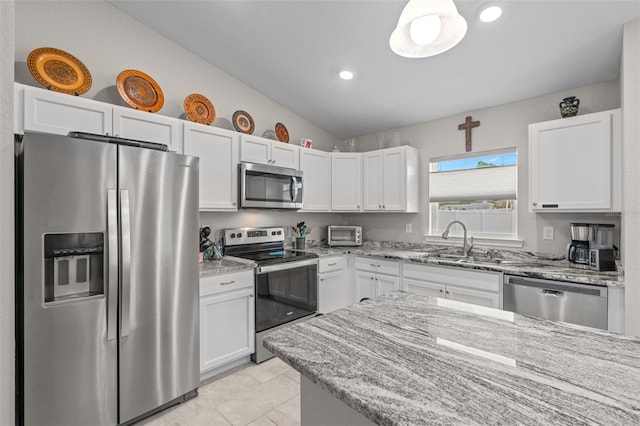 7886 SW 103rd Loop, Ocala, FL 34476 - kitchen featuring light stone counters, lofted ceiling, white cabinetry, a sink, and stainless steel appliances