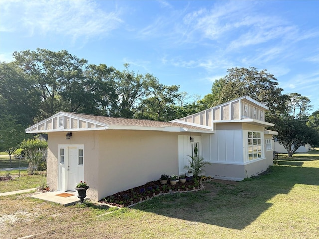view of side of home with board and batten siding, a lawn, and stucco siding