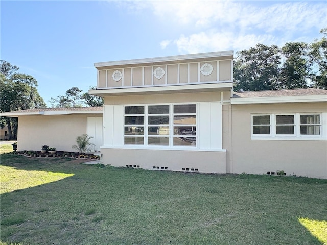 view of front of property featuring roof with shingles, stucco siding, and a front lawn