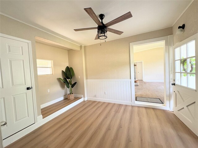 spare room with light wood-style flooring, ornamental molding, and a ceiling fan