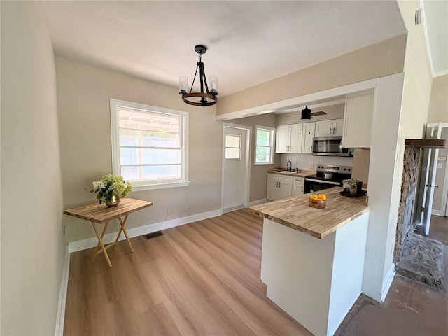 kitchen featuring white cabinetry, visible vents, a sink, stainless steel appliances, and a notable chandelier