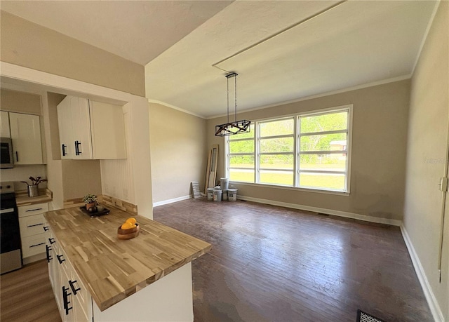 kitchen featuring white cabinetry, wooden counters, stainless steel microwave, and ornamental molding