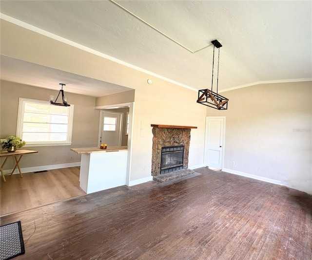unfurnished living room with a stone fireplace, baseboards, vaulted ceiling, crown molding, and wood finished floors