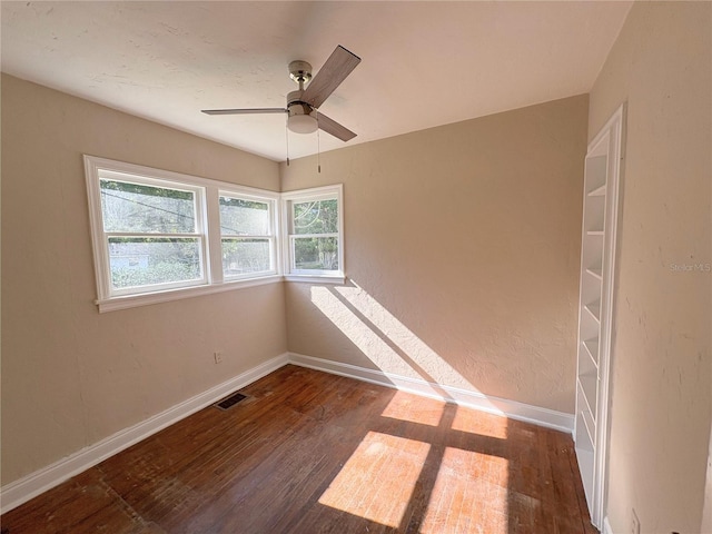 spare room featuring visible vents, baseboards, a ceiling fan, and wood finished floors