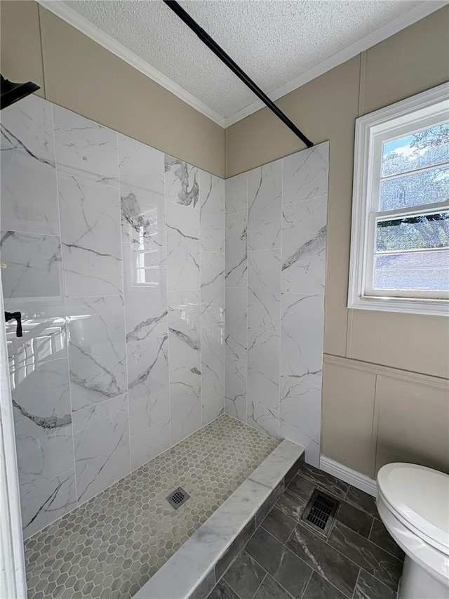 full bath featuring a tile shower, crown molding, a textured ceiling, toilet, and marble finish floor