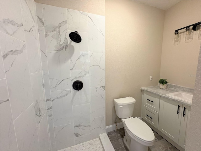 bathroom with toilet, tiled shower, and vanity