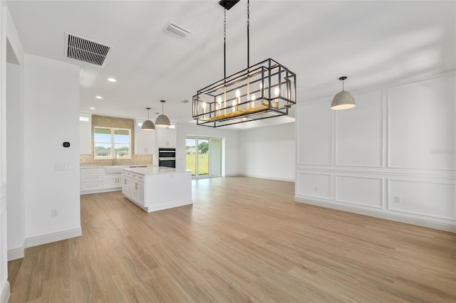 1784 NW 85th Loop, Ocala, FL 34475 - kitchen with open floor plan, light countertops, white cabinetry, a sink, and light wood finished floors