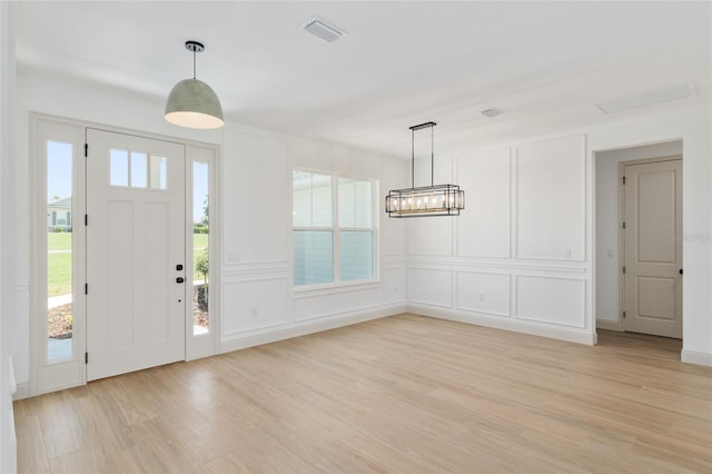 1784 NW 85th Loop, Ocala, FL 34475 - entryway with light wood-style floors, a chandelier, a decorative wall, and baseboards