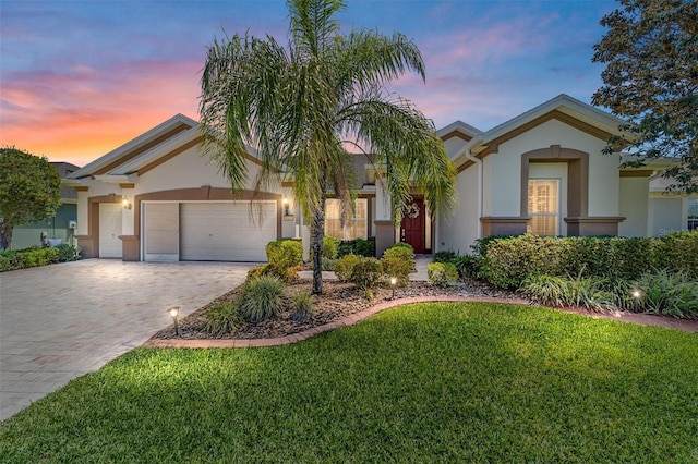 mediterranean / spanish-style house featuring stucco siding, a front yard, decorative driveway, and a garage