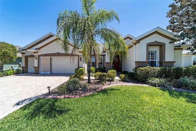 view of front of property featuring stucco siding, decorative driveway, a front yard, and a garage