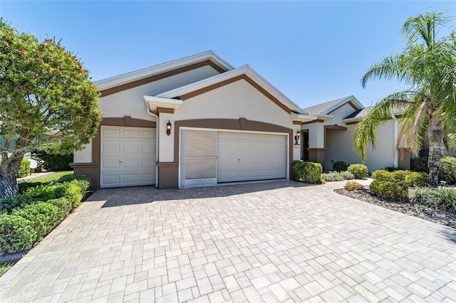 ranch-style house featuring a garage, decorative driveway, and stucco siding