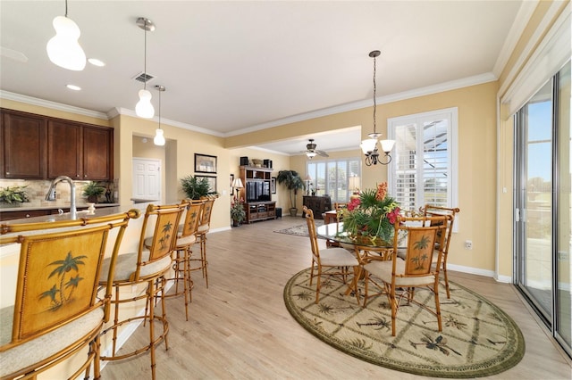 dining room featuring light wood finished floors, an inviting chandelier, visible vents, ornamental molding, and baseboards
