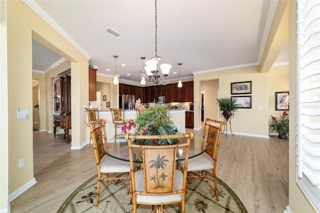 dining space with baseboards, visible vents, an inviting chandelier, and light wood-style floors