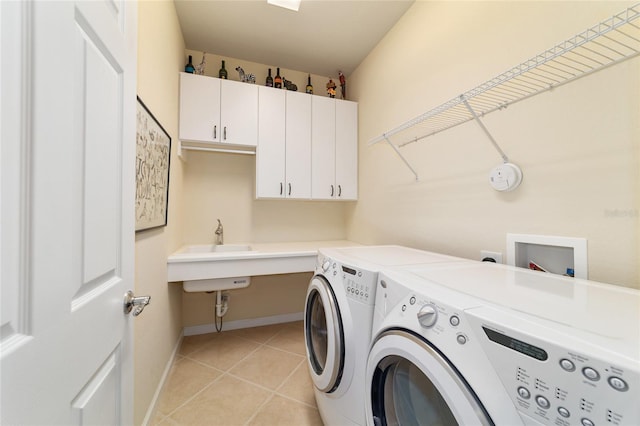 washroom featuring a sink, light tile patterned flooring, baseboards, independent washer and dryer, and cabinet space