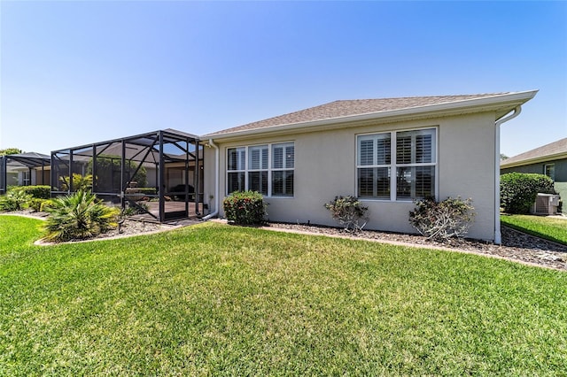 rear view of property with central air condition unit, a lawn, a lanai, and stucco siding