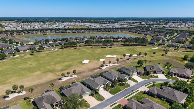 drone / aerial view with golf course view, a residential view, and a water view