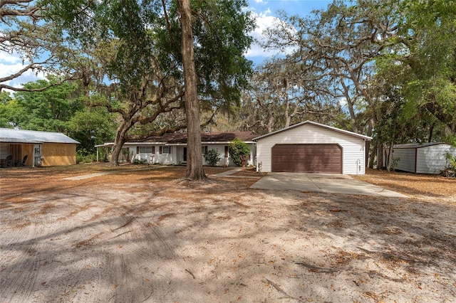 single story home with concrete driveway, an outdoor structure, and a garage