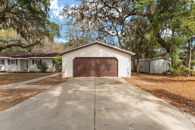 single story home featuring an attached garage, driveway, an outdoor structure, and a shed