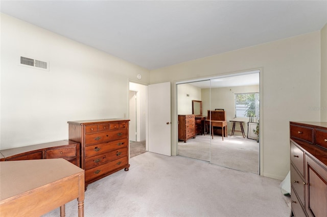 bedroom with light colored carpet, visible vents, and a closet