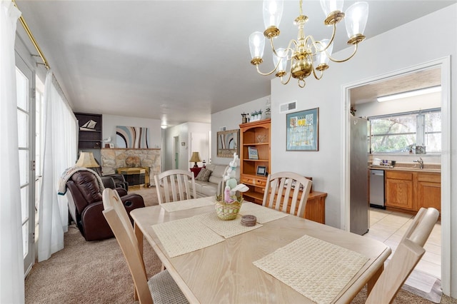 dining space featuring a stone fireplace, a chandelier, and visible vents