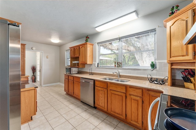 kitchen featuring a sink, appliances with stainless steel finishes, wall chimney range hood, light countertops, and light tile patterned floors