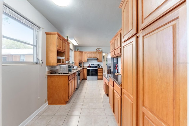 kitchen with decorative backsplash, light tile patterned flooring, stainless steel appliances, baseboards, and under cabinet range hood
