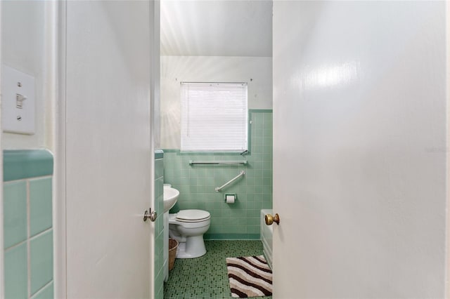 bathroom with wainscoting, toilet, tile patterned floors, and tile walls