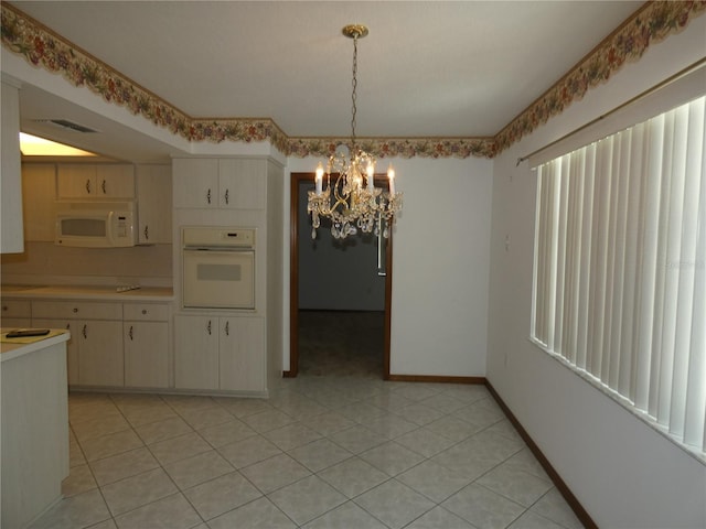 unfurnished dining area featuring visible vents, baseboards, and a notable chandelier