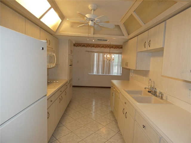kitchen featuring white appliances, light countertops, visible vents, a tray ceiling, and a sink