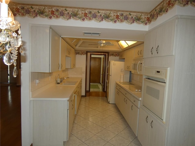 kitchen with light tile patterned floors, white appliances, visible vents, light countertops, and a sink