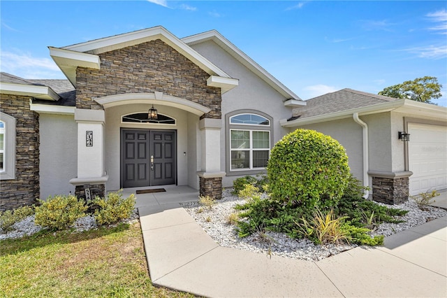 entrance to property featuring stucco siding, an attached garage, and stone siding