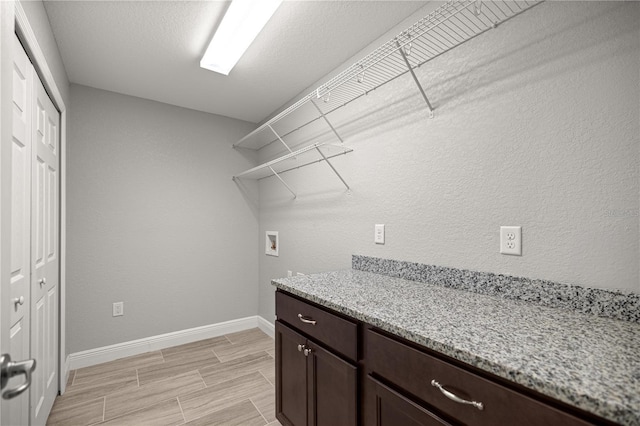 washroom featuring wood tiled floor, baseboards, washer hookup, and cabinet space