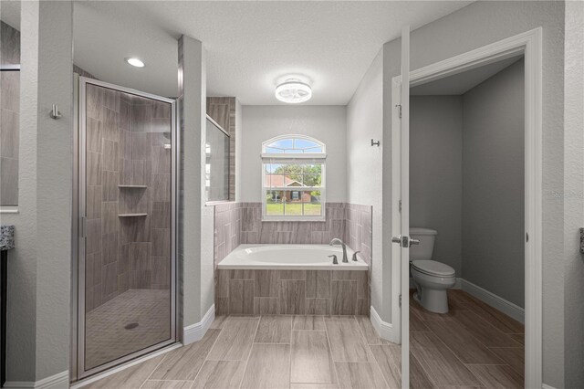 full bathroom with a bath, wood tiled floor, a shower stall, and toilet