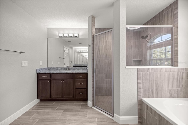 bathroom featuring tiled tub, vanity, a textured ceiling, and a shower stall