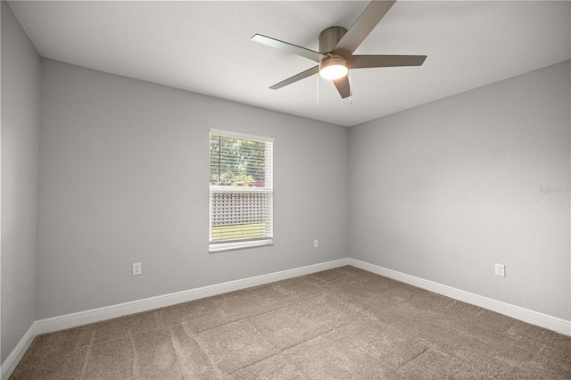 carpeted spare room with ceiling fan and baseboards