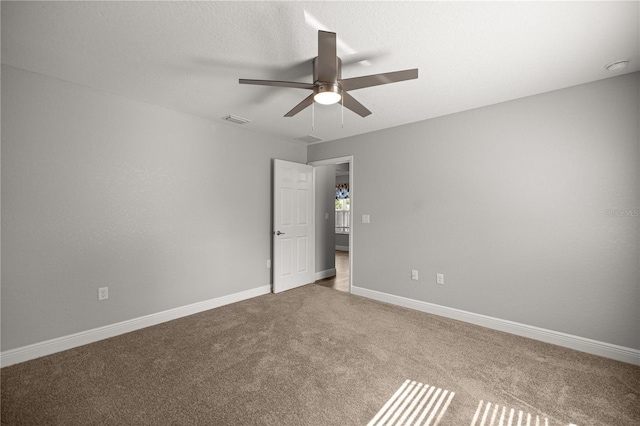 spare room featuring visible vents, a ceiling fan, baseboards, and carpet