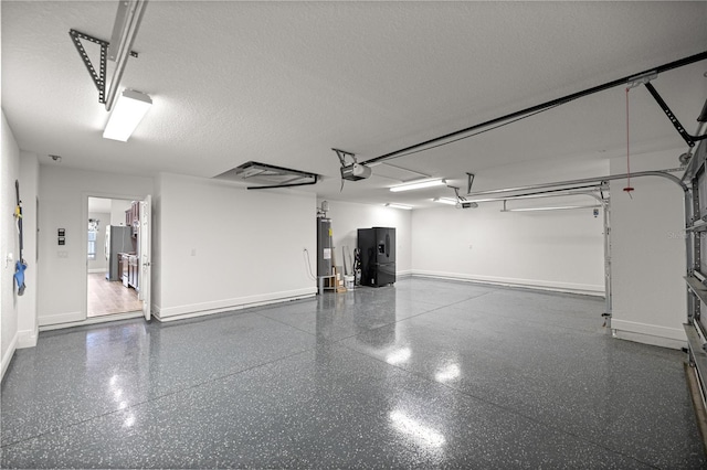 garage featuring a garage door opener, black fridge, electric water heater, and baseboards