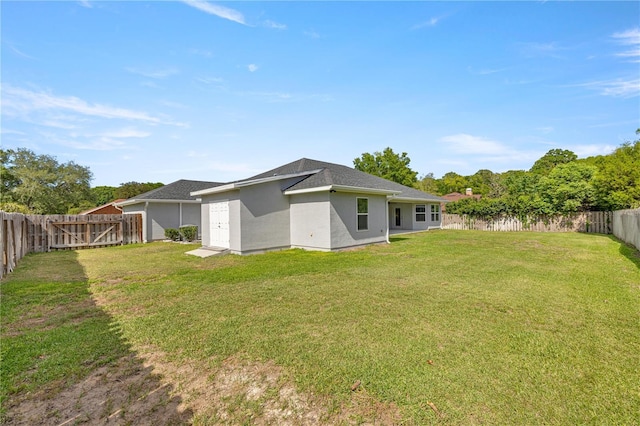 rear view of house featuring a yard, a fenced backyard, and stucco siding