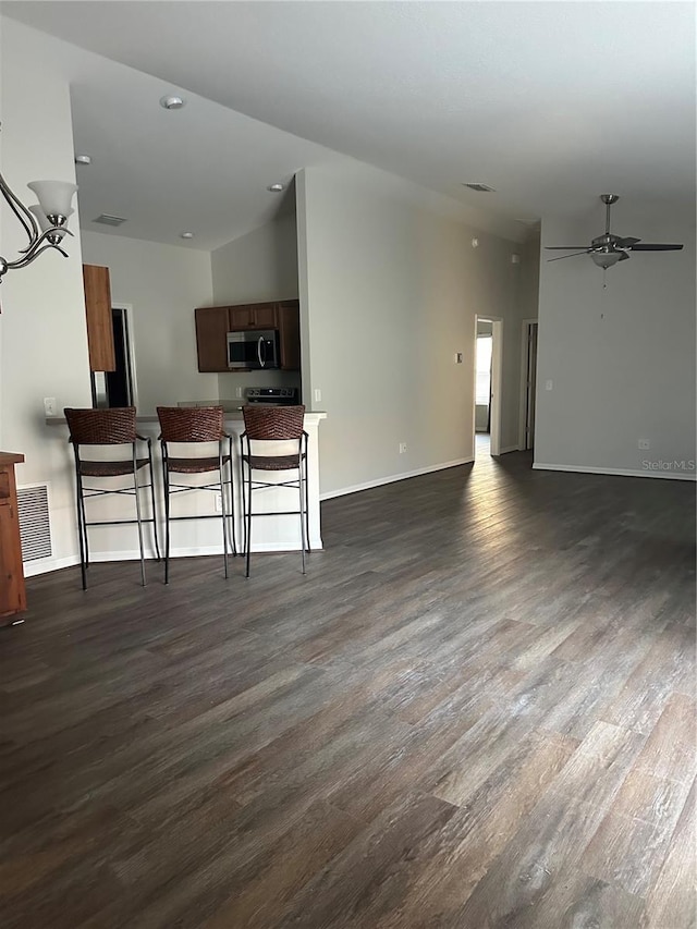 living area with dark wood finished floors, visible vents, baseboards, and ceiling fan