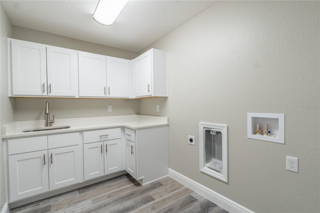 laundry room with washer hookup, cabinet space, a sink, baseboards, and light wood finished floors