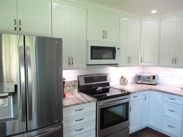 kitchen featuring light stone countertops, a toaster, backsplash, and appliances with stainless steel finishes