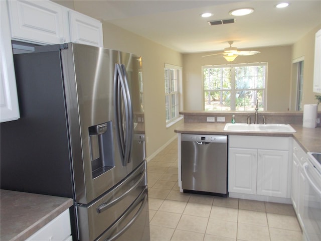 11653 SW 72nd Cir, Ocala, FL 34476 - kitchen with stainless steel appliances, a sink, light tile patterned floors, a peninsula, and white cabinetry