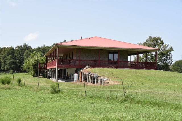 rear view of house with a wooden deck, a lawn, and metal roof
