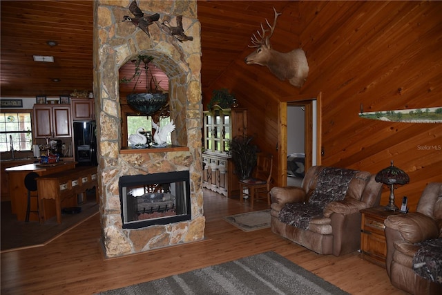 living area featuring a fireplace, wooden walls, wood finished floors, and wooden ceiling
