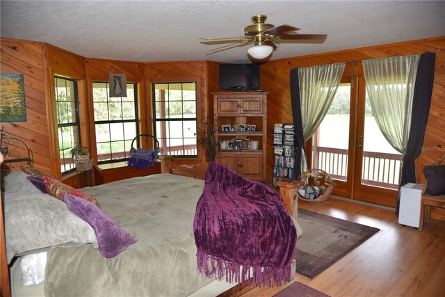 bedroom with wooden walls, wood finished floors, and access to outside