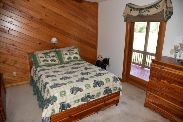 bedroom featuring wooden walls, carpet floors, access to exterior, and multiple windows