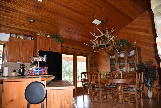 dining room featuring wooden walls, a bar, wooden ceiling, french doors, and a chandelier