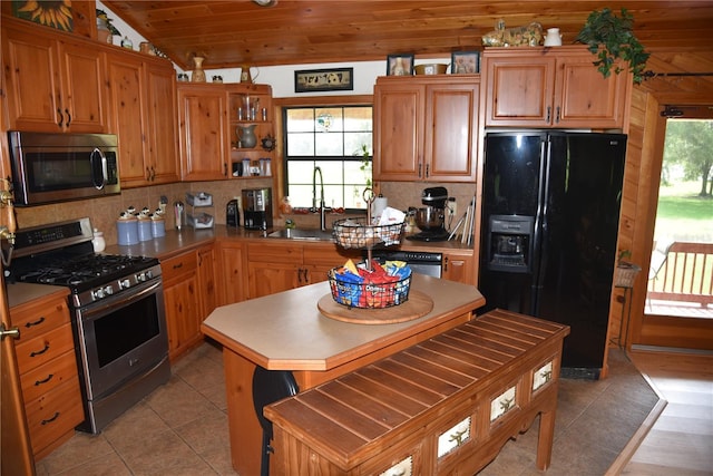 kitchen featuring backsplash, vaulted ceiling, a sink, light tile patterned flooring, and appliances with stainless steel finishes